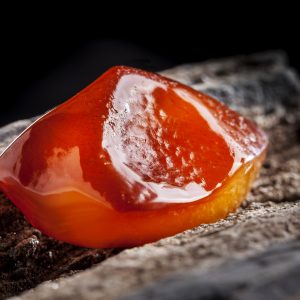 Natural amber. A piece of yellow and red semi transparent natural amber on piece of stoned wood