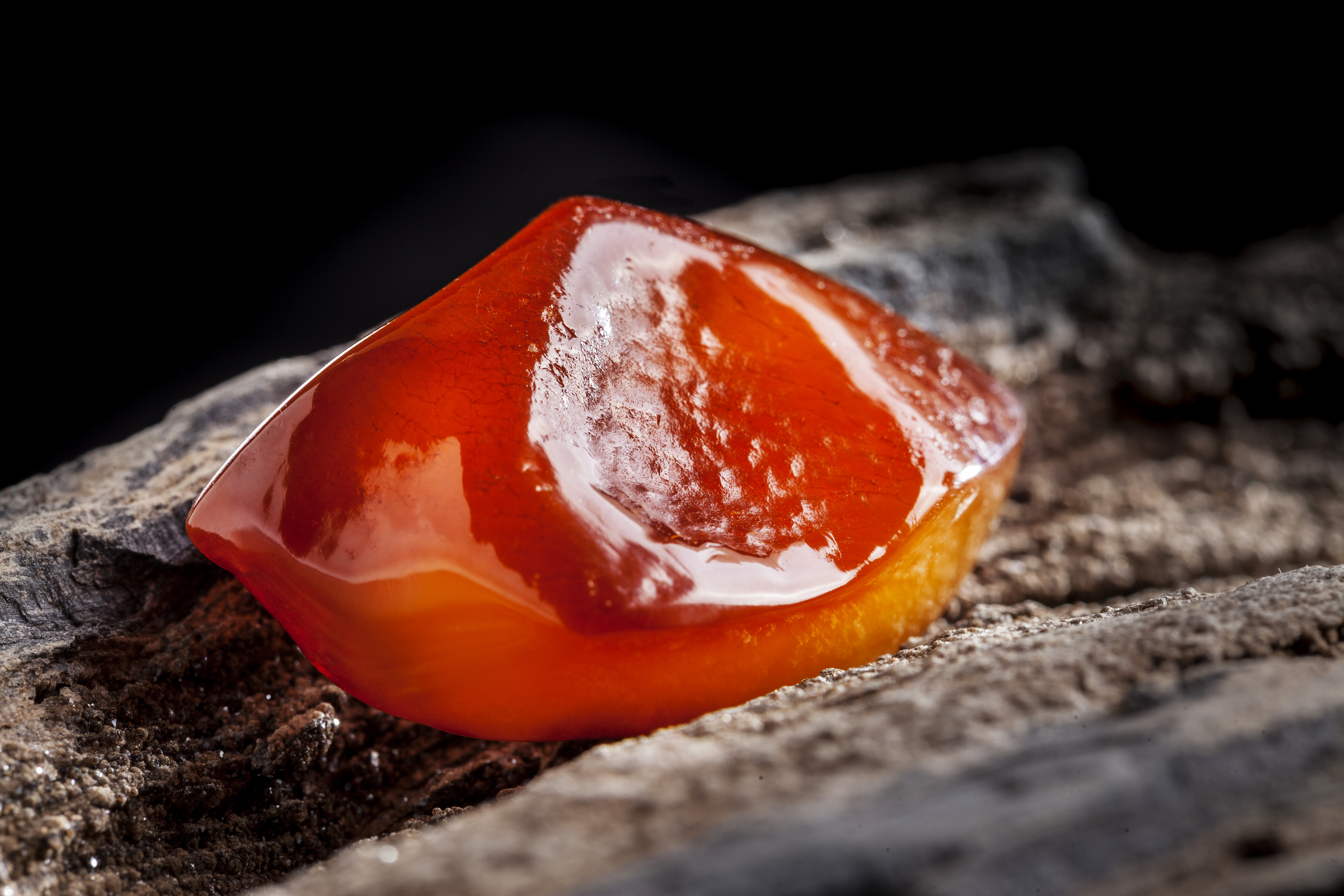 Natural amber. A piece of yellow and red semi transparent natural amber on piece of stoned wood